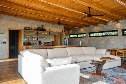 a living room with a white couch and a kitchen at Seabird - Villa 6 in Placencia Village