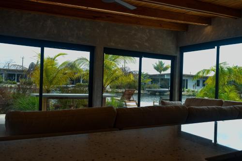 a living room with a couch and large windows at Seabird - Villa 6 in Placencia Village