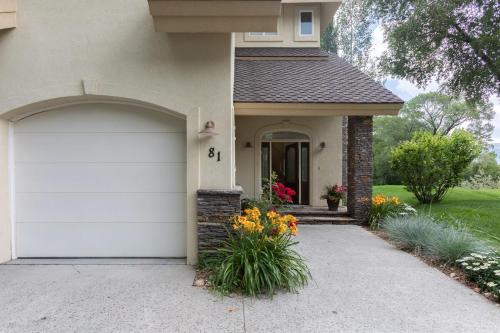 a house with a white garage door and flowers at Beautiful Driggs Townhome with Views and Hot Tub in Driggs