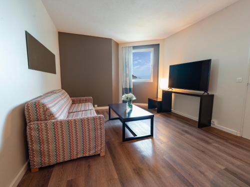 a living room with a couch and a tv at Novotel Dakar in Dakar