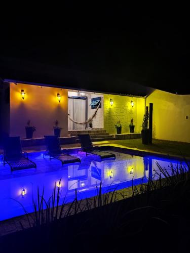 a patio with chairs and a pool at night at Casa do Aconchego OFICIAL in Pirenópolis