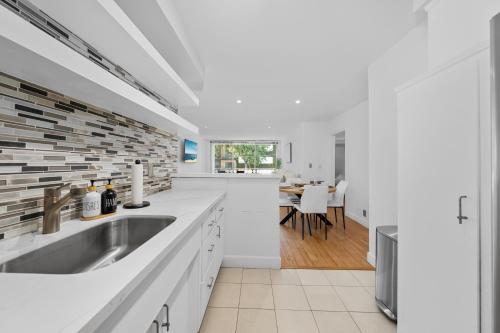 a white kitchen with a sink and a dining room at The Orchid-Beachfront Bliss Spacious 2BR Apt In Santa Monica in Los Angeles