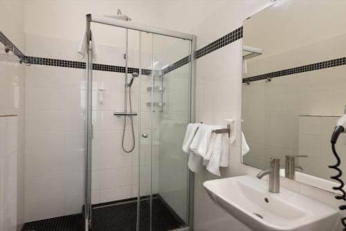 a bathroom with a glass shower and a sink at Salvatore Prague Rooms in Prague
