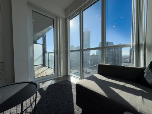 a living room with a couch and large windows at Comfy Front Wellington Suites CN Tower Rogers Centre & Free Parking in Toronto