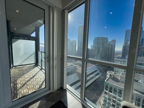 a room with windows and a view of a city at Comfy Front Wellington Suites CN Tower Rogers Centre & Free Parking in Toronto
