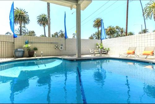 a large blue swimming pool with chairs and palm trees at The Orchid-Beachfront Bliss Spacious 2BR Apt In Santa Monica in Los Angeles