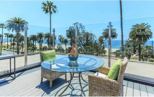 a glass table and chairs on a balcony with the beach at The Orchid-Beachfront Bliss Spacious 2BR Apt In Santa Monica in Los Angeles