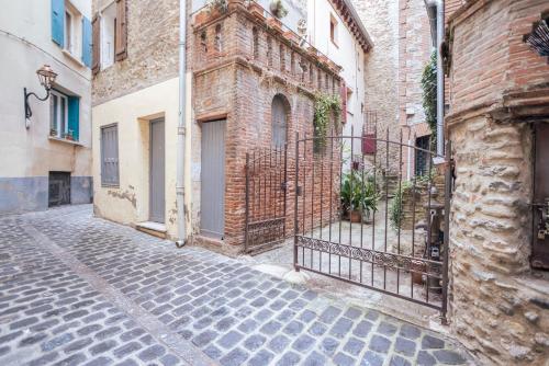 an alley with a brick building and a gate at Au Petit Paris, Centre de Céret in Céret