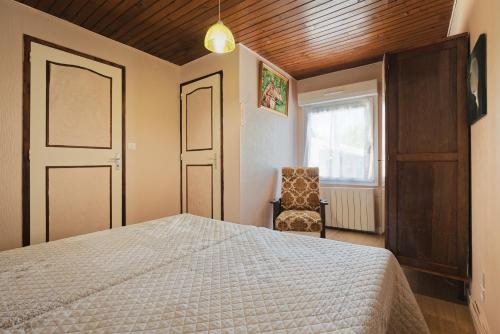 a bedroom with a bed and a chair and a window at La petite maison in Monthault