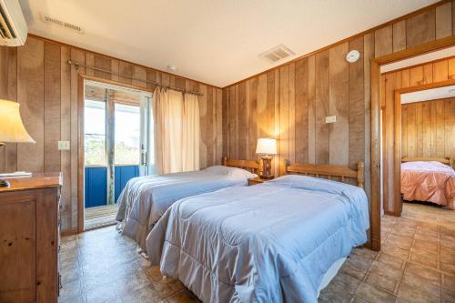 two beds in a room with wooden walls at Laughing Place - Southern Shores, 175 Ft to Beach, Pool Table, Pets OK, Flex Stays in Southern Shores