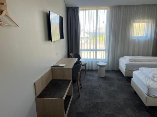 a hotel room with two beds and a desk and a bed at Hotel Natur Akureyri in Akureyri