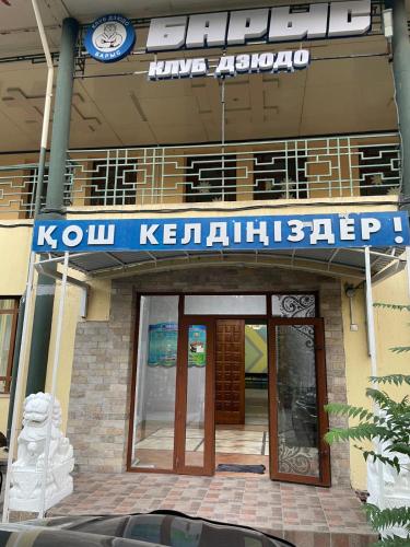 a building with a blue sign on the front of it at Барыс in Shymkent