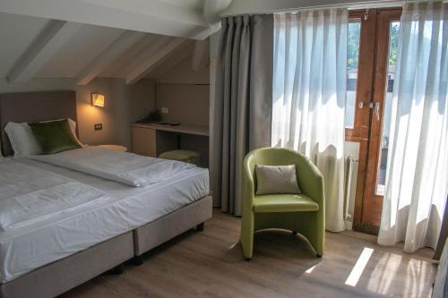 a bedroom with a bed and a chair and a window at Alchimia WellResort in Comano Terme