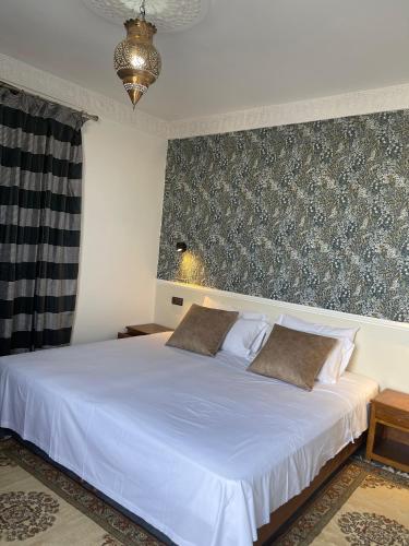 a bedroom with a white bed with a wall at Diaft'na in Marrakech