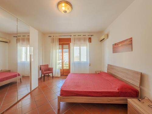 a bedroom with a red bed and a chair at La Casa di Dario - Super Luminosa - 5' dal mare in Albinia