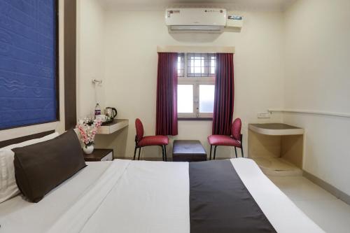 a bedroom with a bed with red chairs and a window at Super Capital O Prestige in Hyderabad