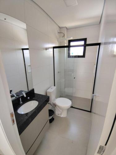 a white bathroom with a toilet and a sink at Apartamento Le Vert in Barretos