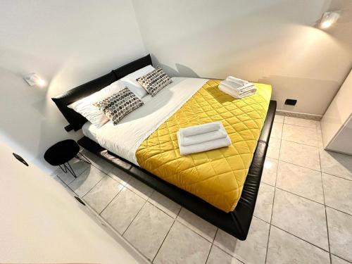 a bedroom with a bed with yellow sheets and towels at LUXURY APARTMENT OPEN SPACE with garden & free parking in Turin