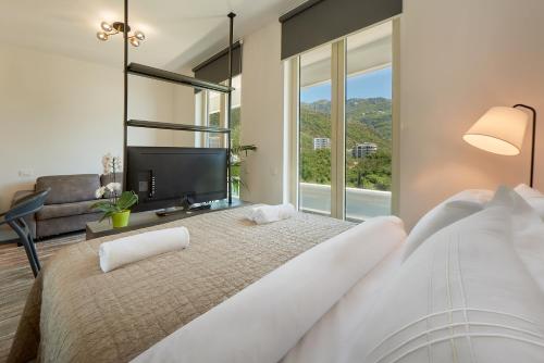 a bedroom with a large bed with a large window at Skyline Sunset in Becici