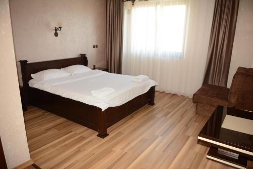 a bedroom with a bed and a couch and a window at Hotel Ulpiana, Ethno House in Gracanica