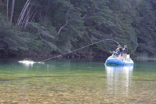 a couple of people on a raft in the water with a pole at Entre Rios Lodge in Ranco