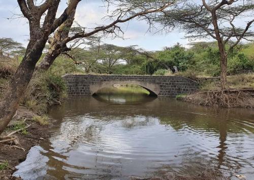 a brick bridge over a river in a field at Kitengela Cabin in Kajiado