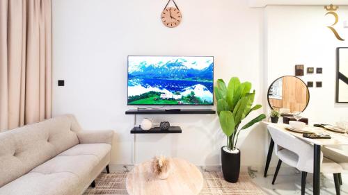 a living room with a couch and a tv on a wall at Stylish 1BR - Maryah Vista Luxe Escape in Abu Dhabi