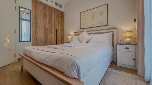 a bedroom with a large white bed with a wooden headboard at Stylish 1BR - Maryah Vista Luxe Escape in Abu Dhabi