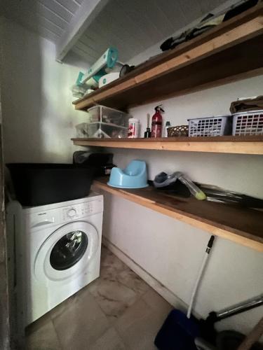 a laundry room with a washing machine and shelves at Le Jasmin de nuit Chalet , SPA Privatif in Les Abymes