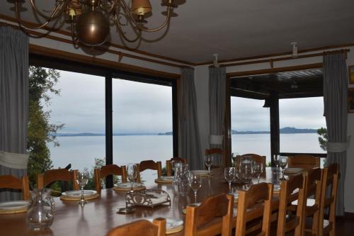 a dining room with a table with chairs and windows at Entre Rios Lodge in Ranco