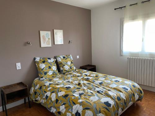 a bedroom with a bed with a yellow and blue blanket at Grand appartement proche centre ville et Rocamadour in Gramat