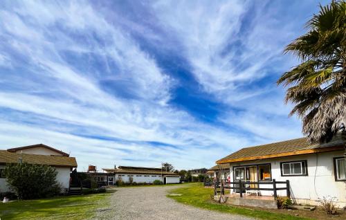 a cloudy sky above a house with a palm tree at Cabañas Las Terrazas in Pichilemu