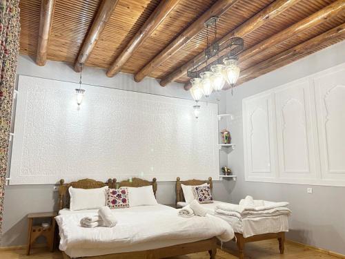 two beds in a room with white sheets at Old town guest house in Bukhara
