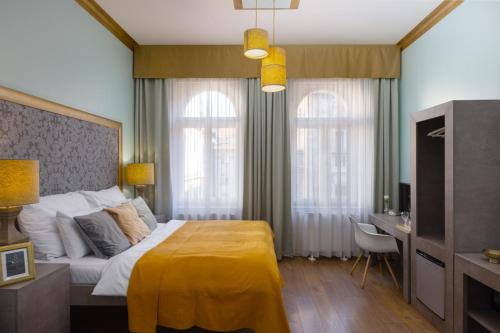 a bedroom with a large bed with a yellow blanket at Salvatore Prague Rooms in Prague