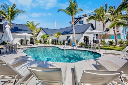 a swimming pool in front of a house with palm trees at The Retreat at Anna Maria Island Inn in Bradenton Beach