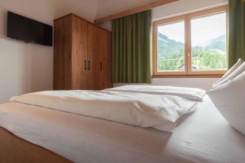 a bedroom with a large white bed with a window at Appartement Pension Strolz in Bichlbach