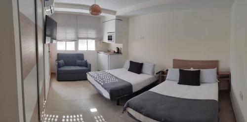 a hotel room with two beds and a chair at Hostal Casa Miguel Marbella in Marbella