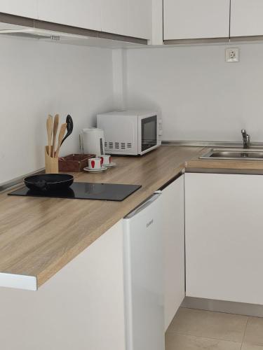 a kitchen with white cabinets and a microwave on a counter at Hostal Casa Miguel Marbella in Marbella