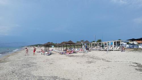 a group of people on a beach with chairs and umbrellas at Villa Filia in Almiros Beach