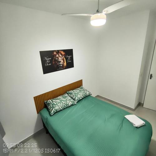1 dormitorio con 1 cama con sábanas verdes y una foto en Jockey of Itaparica 1, en Vila Velha
