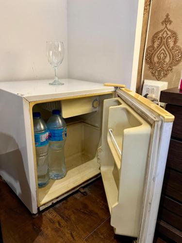an open refrigerator with water bottles and a wine glass at Lyallpur Home Stay in Faisalabad