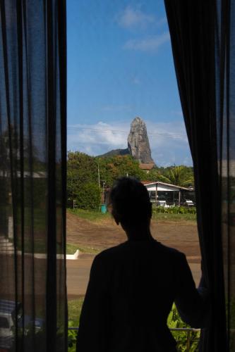 a woman looking out a window at a rock at Triângulo Noronha in Fernando de Noronha