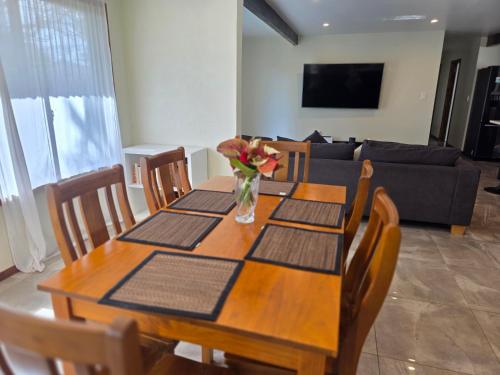 a dining room table with a vase of flowers on it at Atupa Holiday Home in Rarotonga