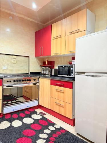 a kitchen with red cabinets and a white refrigerator at Superb & comfy 3BDR apartment with outstanding view شقة فندقية فاخرة فيو رائع للمطار in Cairo