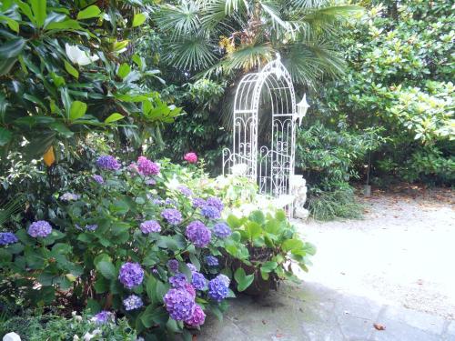 a garden with a white gate and purple flowers at Cuore Verde in Cavour