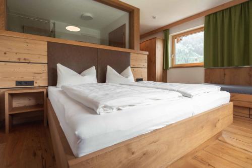 a large white bed in a room with a mirror at Appartement Pension Strolz in Bichlbach