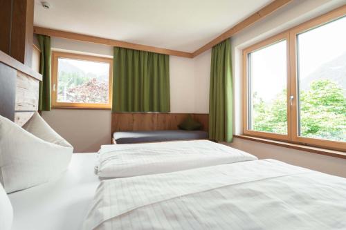 two beds in a room with two windows at Appartement Pension Strolz in Bichlbach