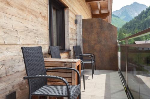 a balcony with chairs and a desk and a window at Appartement Pension Strolz in Bichlbach