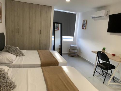 a hotel room with two beds and a desk at Apartamento Cartagena en el laguito bocagrande vista al mar in Cartagena de Indias