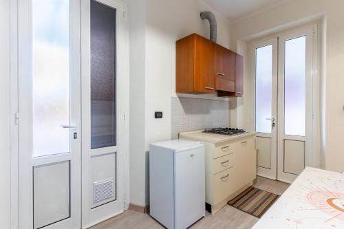 a kitchen with a stove and a white refrigerator at Zen Retreat per Coppie con Jacuzzi - Dehor e Garage Privato - Check in Automatico 24 7 in Casale Monferrato